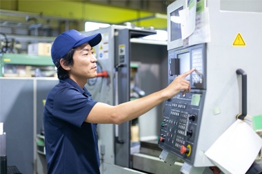 製造機械パネルを操作する社員